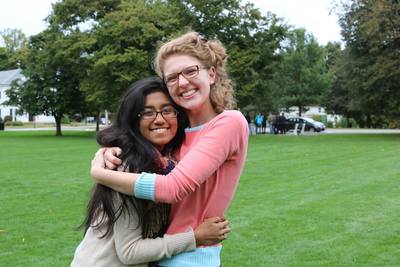 Two Collegium singers standing on a lawn hugging.