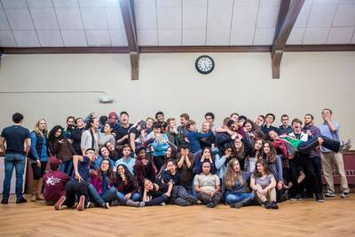 The entire Harvard-Radcliffe Collegium Musicum making silly faces and posing for photo in a large community room while on choir retreat.